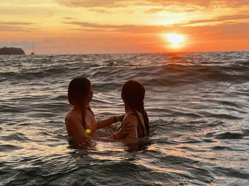 Kaylee and her friend in the ocean in Costa Rica at sunset.