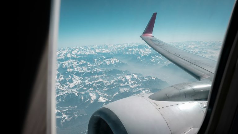 Looking out the window of an airplane at the wing and the city below
