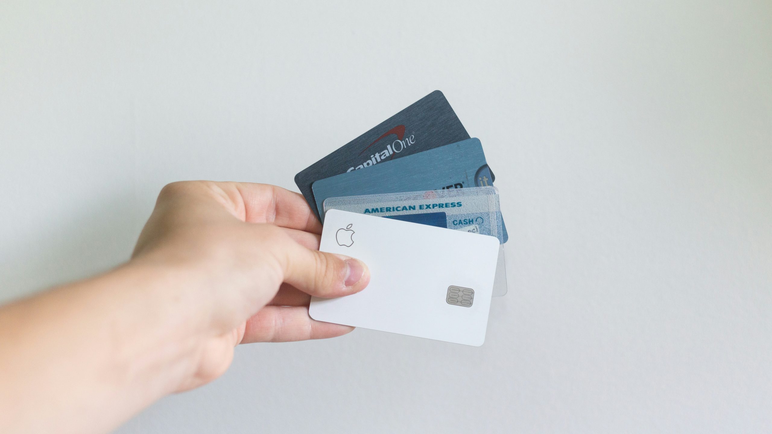 A hand holding four credit cards